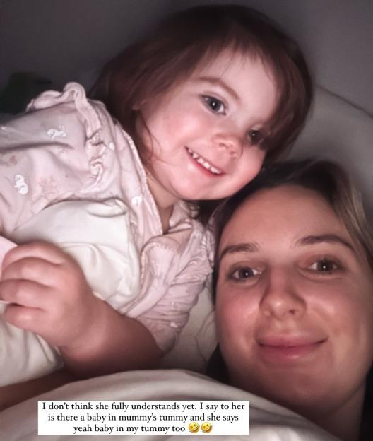 Photo of a woman and young child in bed; text overlay asks if the child is excited to be a big sister.