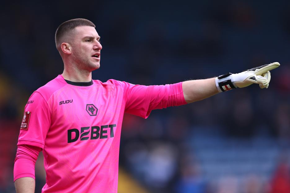 Sam Johnstone of Wolverhampton Wanderers in a pink goalkeeper jersey, pointing.