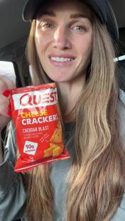 Woman holding a bag of Quest Cheddar Blast Cheese Crackers.
