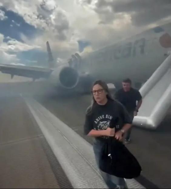 American Airlines plane's landing gear on fire; passengers evacuating via inflatable slide.