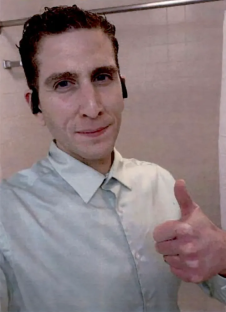 Man in a light gray shirt giving a thumbs up.