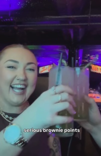 Woman holding a large drink and smiling.