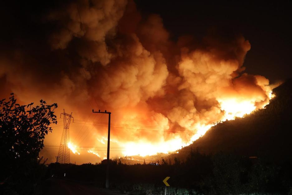 Large wildfire at night engulfing a hillside.