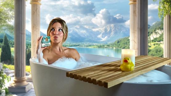 Woman in a bubble bath holding a bar of soap.