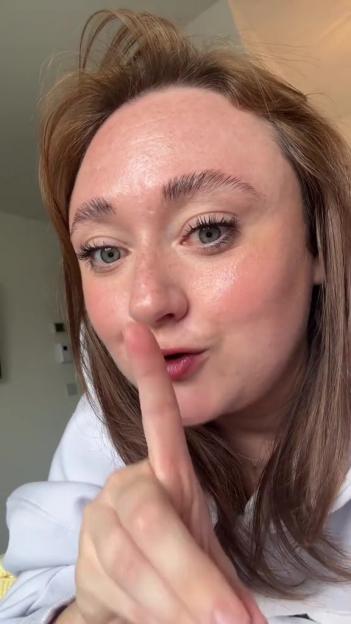 Woman holding a finger to her lips, gesturing for silence.