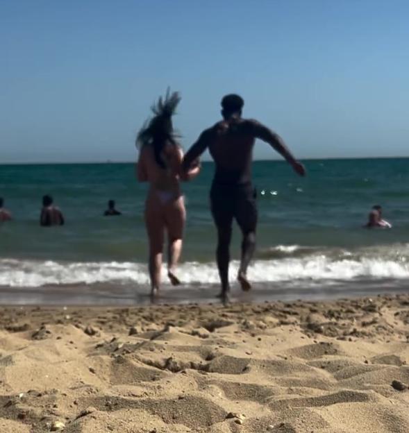 Couple running into the ocean on a beach.
