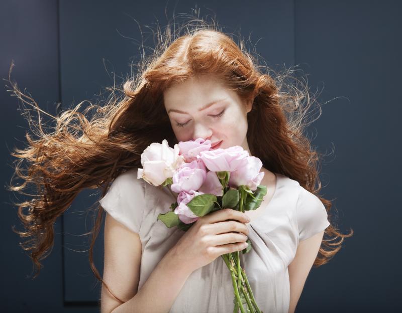 Woman smelling a bouquet of roses.