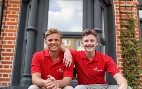 Jeff Brazier and his son Bobby Brazier sitting outside a building, wearing red HomeServe polo shirts.