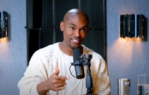 Man speaking into a microphone during a podcast recording.