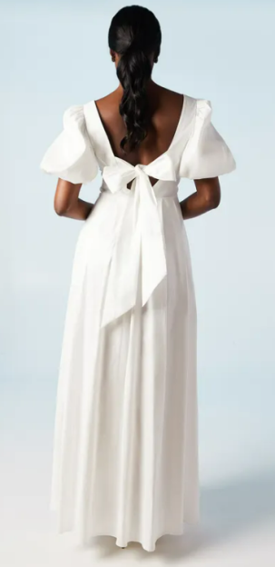Woman in white maxi dress with bow back detail.