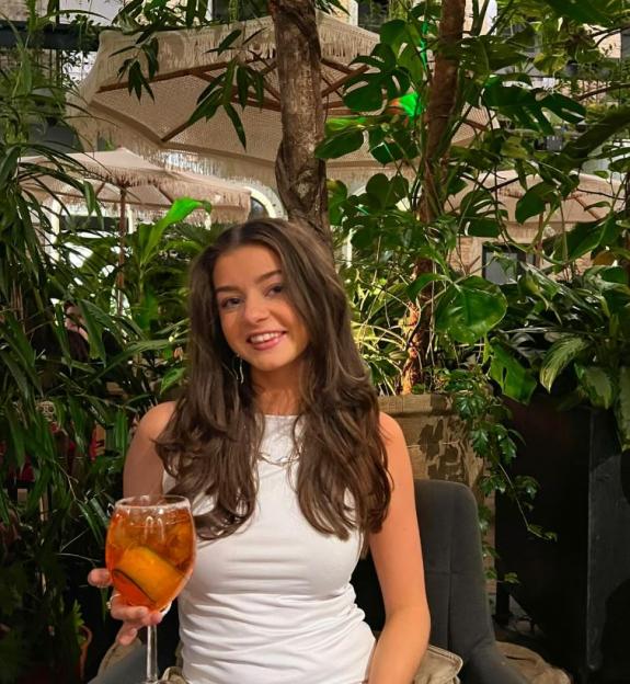 Woman holding an Aperol Spritz in a lush garden setting.
