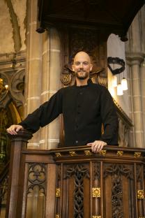 Glyn Wise, former Big Brother contestant, training to be a priest, standing at a church pulpit.