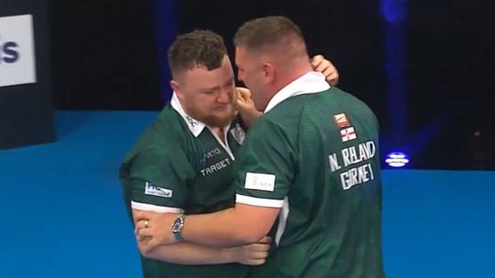 Two dart players embracing, one of whom is crying.