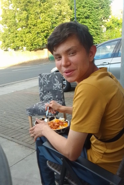 A young man eating a meal outdoors.
