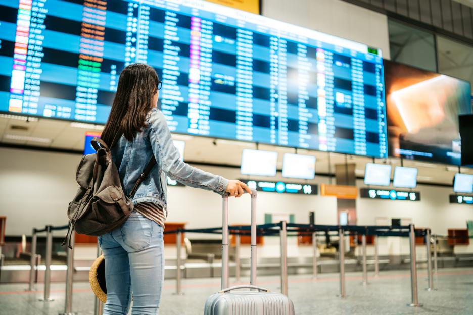 Woman at an airport checking a departures board.
