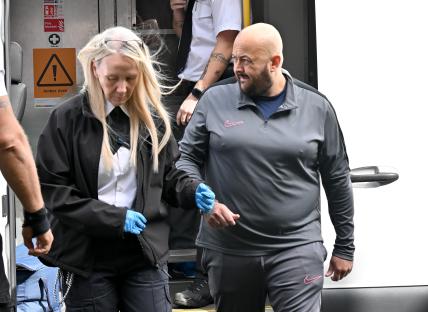 A man in handcuffs being escorted by a police officer.
