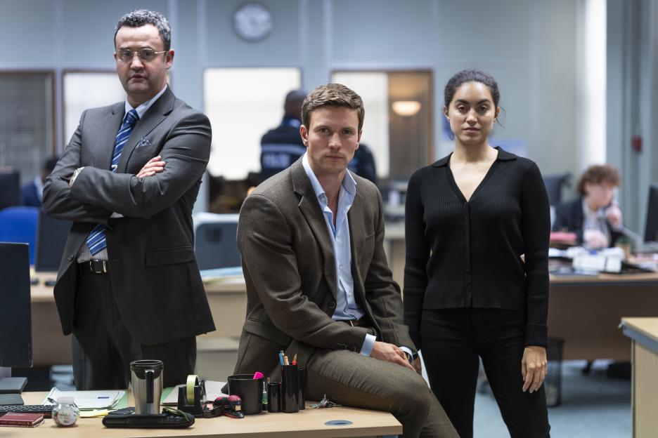 Three colleagues stand in an office.