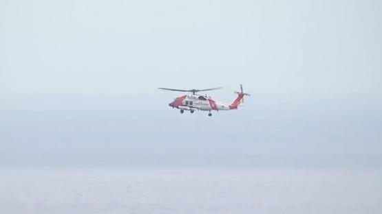 Coast Guard helicopter in flight over water.