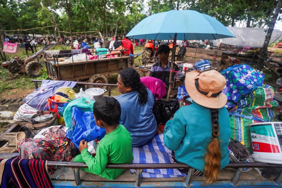 Cambodian civilians evacuate, carrying belongings on a cart.