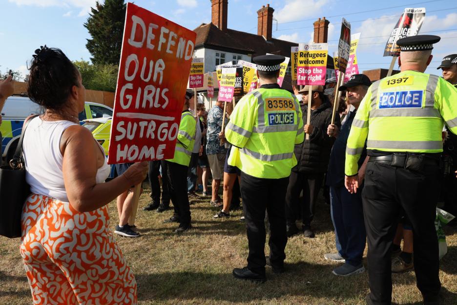 Protestors holding signs during a demonstration outside a hotel.