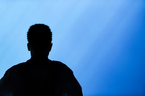 Silhouette of a man gazing at an aquarium.