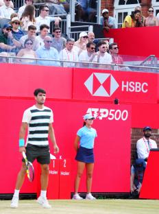 Emma Raducanu laughs while watching Carlos Alcaraz play tennis.