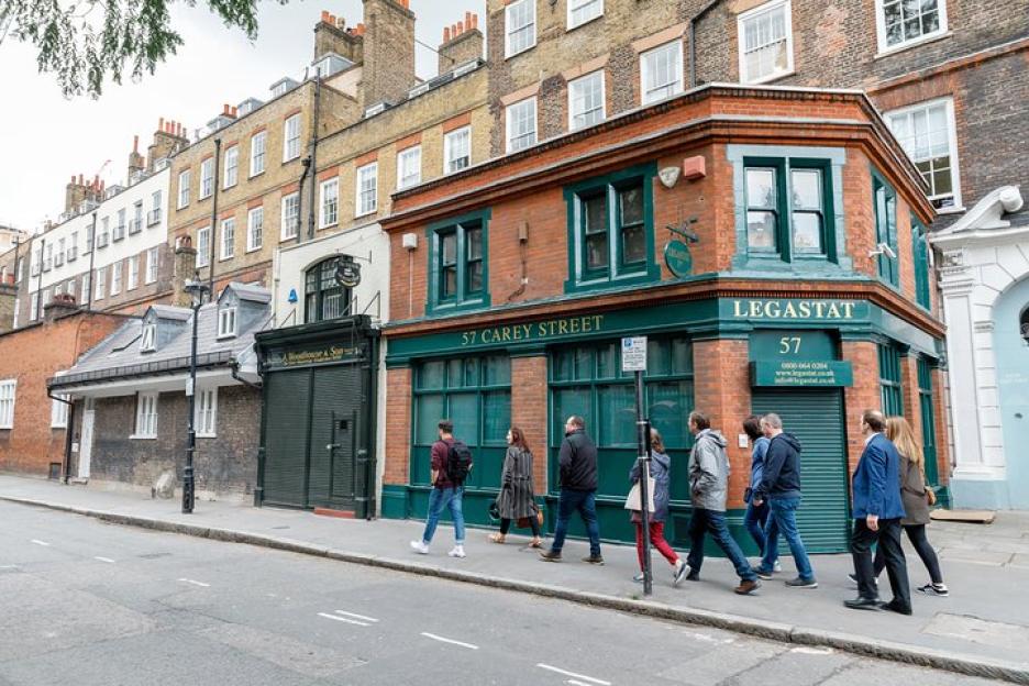 A group of people walking past Legastat, a building at 57 Carey Street, London.