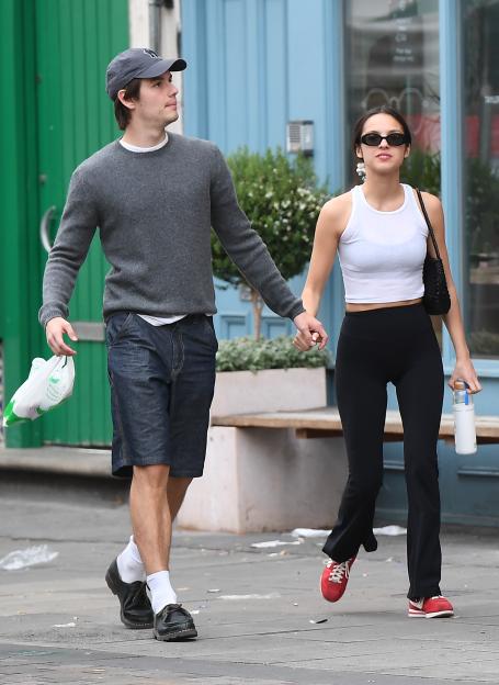 Olivia Rodrigo and Louis Partridge holding hands and walking down the street.