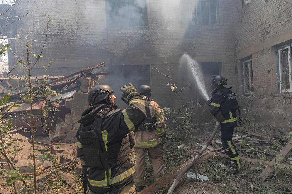 Ukrainian emergency service workers extinguish a fire at a bombed-out school.
