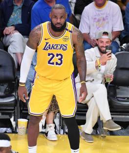 LeBron James in a Lakers uniform, another man taking a photo of him.