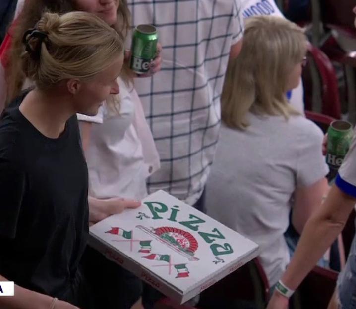 Woman holding a pizza box in a crowd.