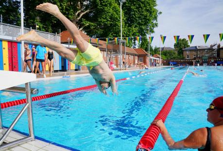 Man diving into outdoor swimming pool.