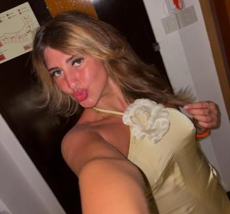 Woman in a pale yellow dress making a kissy face.