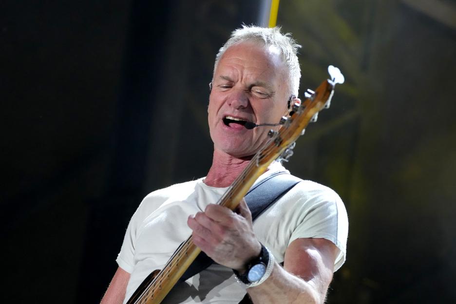 Sting performing onstage with a bass guitar.