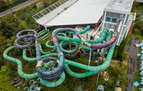 Aerial view of an abandoned water park with overgrown vegetation.
