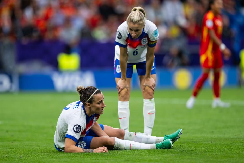 Lucy Bronze of England sits on the ground during a soccer match.
