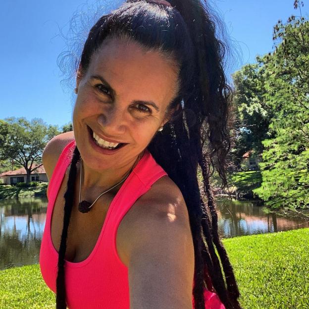 Woman with dreadlocks smiling outdoors.