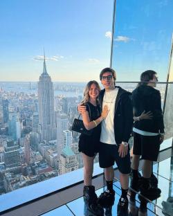 Couple posing in front of a New York City view with the Empire State Building in the background.