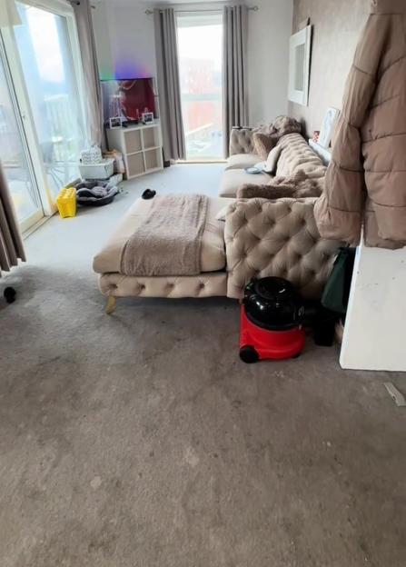 Living room with dirty carpet and sectional sofa.