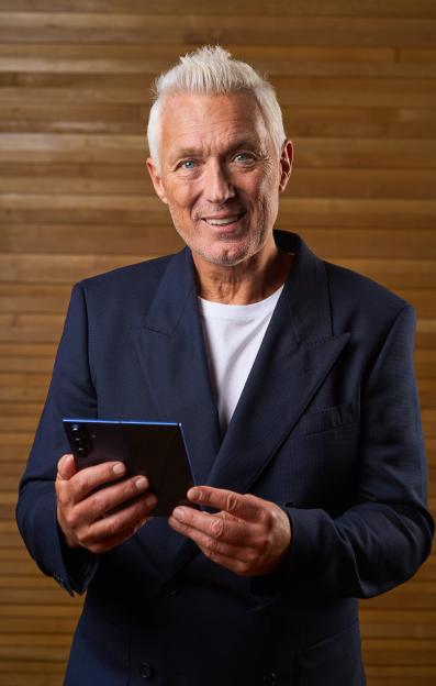 Smiling man in a suit using a smartphone.