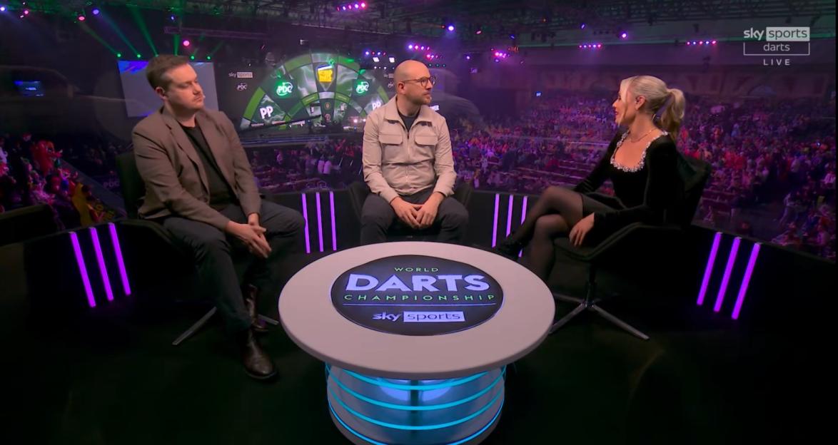 Three people on a darts championship panel.