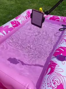 Tablet propped above a pink inflatable pool.