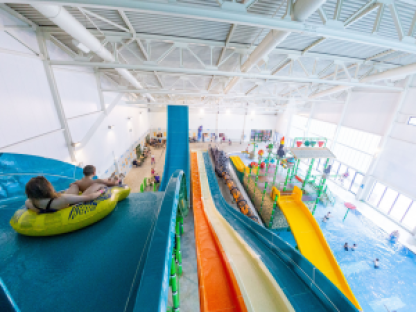 Aerial view of an indoor water park with slides and people.