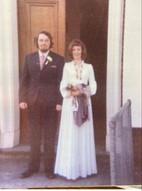 Photo of a wedding couple posing outside a building.