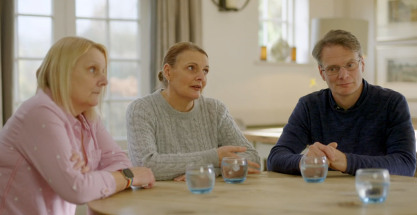 Three people sitting around a table, listening intently.