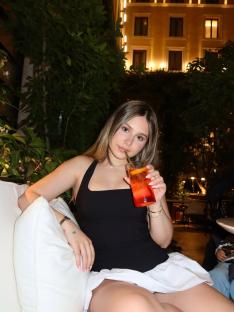 Woman sitting outdoors at night holding a cocktail.