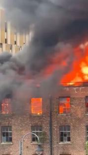 Large fire engulfing a brick building in Manchester.
