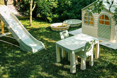 Children's plastic playset in a backyard.