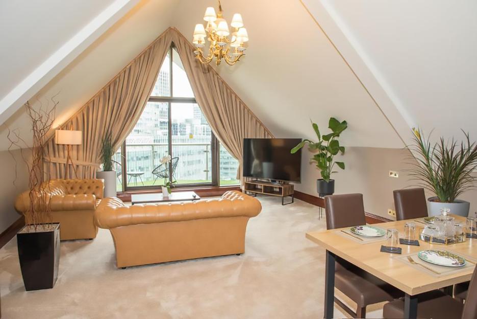 Tan leather sofa and dining area in a hotel suite with city views.