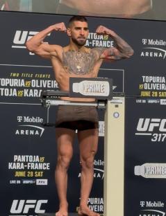 A fighter flexing his biceps at the weigh-in.